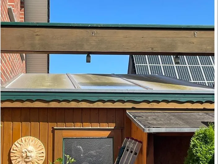 Überdachung am Gartenhaus vor der Reinigung, grauer Belag auf den Platten