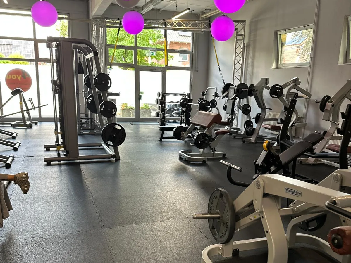 Trainingsfläche eines Fitnessstudios mit Geräten und frisch gereinigtem Boden